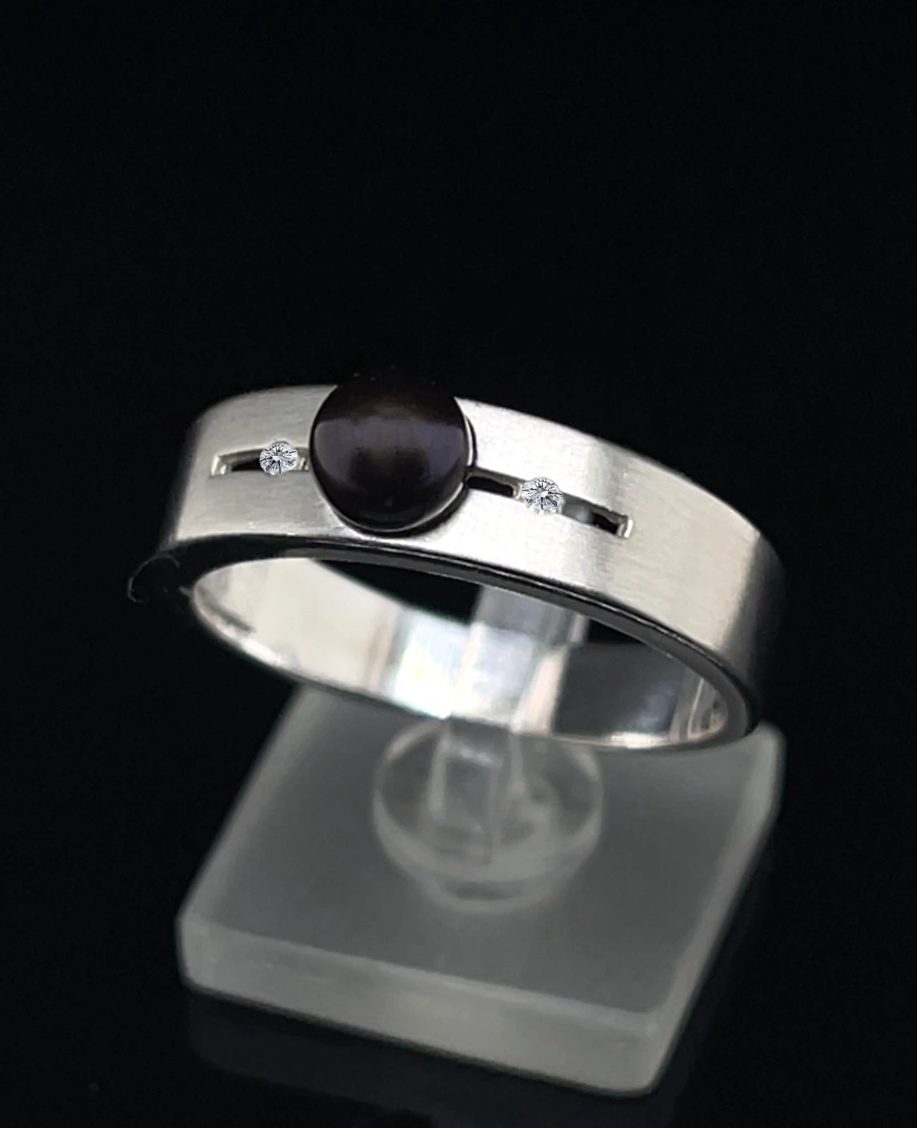 Breite ringschine mittig offener dünner rechteckiger spalt große schwarze perle rechts und links davon je 1 Diamant