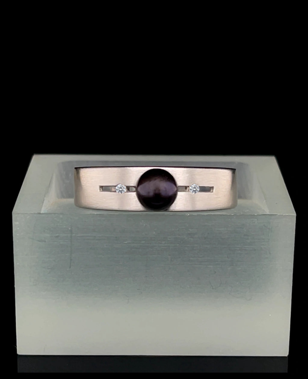 Breite ringschine mittig offener dünner rechteckiger spalt große schwarze perle rechts und links davon je 1 Diamant