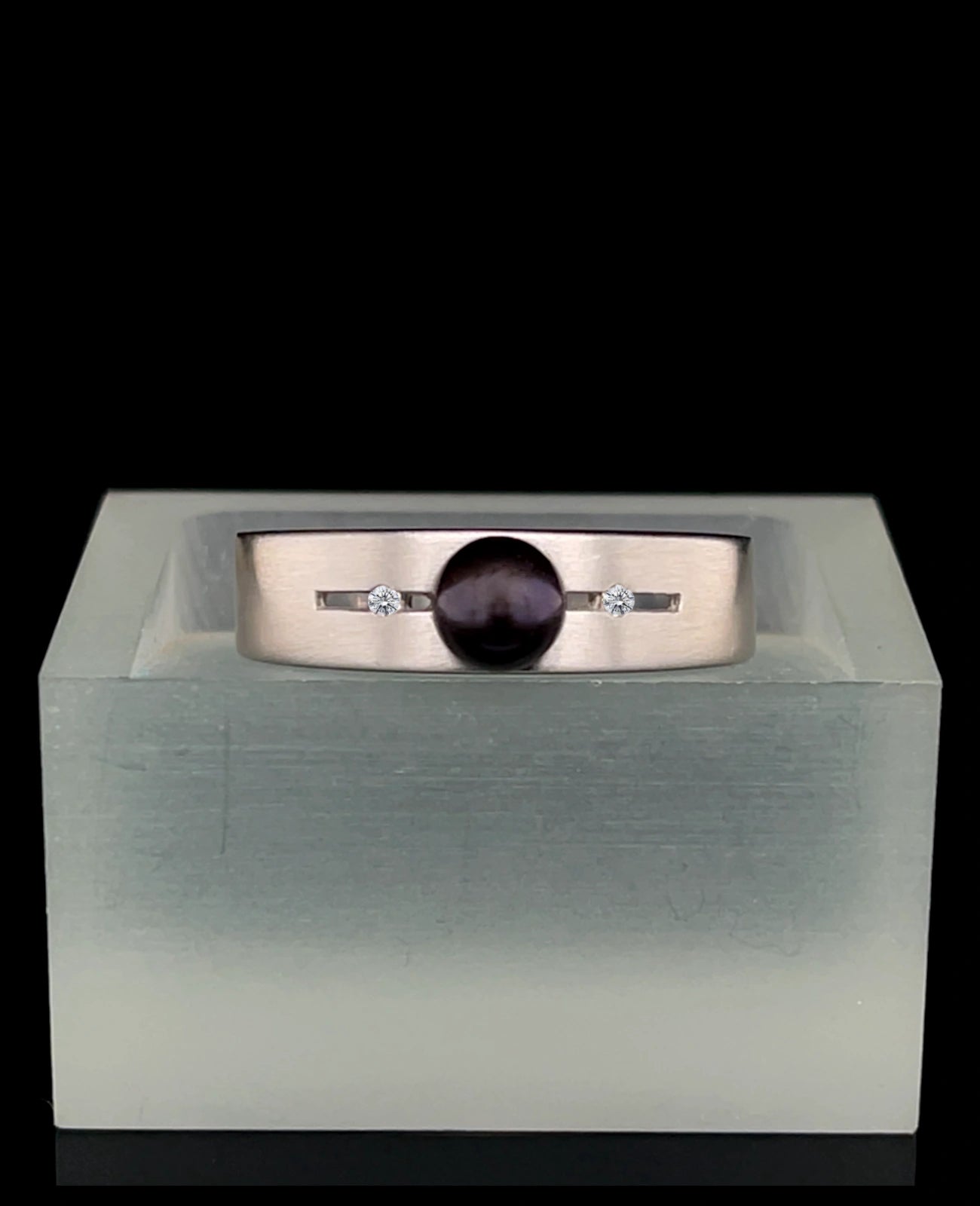 Breite ringschine mittig offener dünner rechteckiger spalt große schwarze perle rechts und links davon je 1 Diamant
