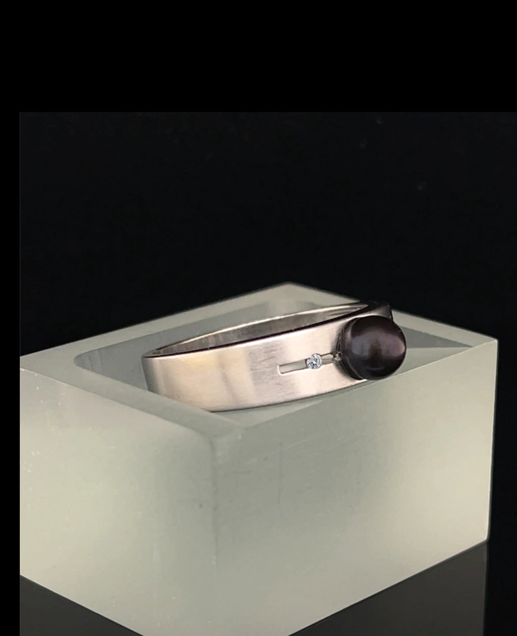 Breite ringschine mittig offener dünner rechteckiger spalt große schwarze perle rechts und links davon je 1 Diamant