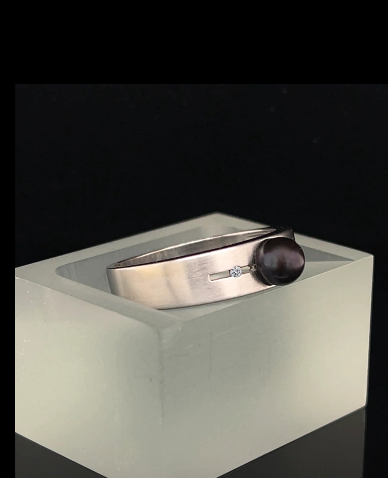 Breite ringschine mittig offener dünner rechteckiger spalt große schwarze perle rechts und links davon je 1 Diamant